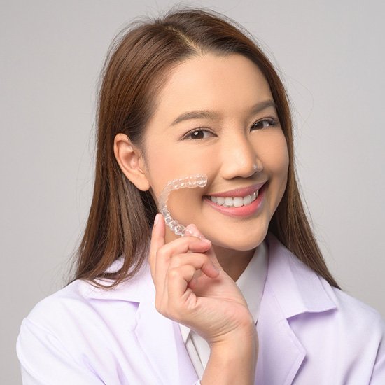Smiling patient holding clear aligner