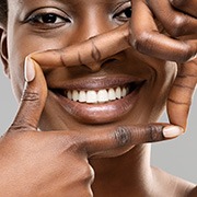 Woman framing her bright smile with four fingers