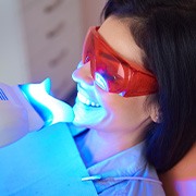 Woman with dark hair in dental chair having teeth whitened