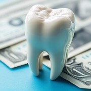 Large model tooth in front of dollar bills blurry in background