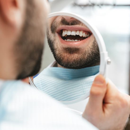 Man’s smile reflected in handheld mirror