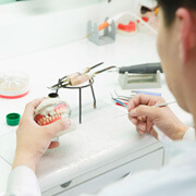 Lab tech wearing white working on a set of dentures