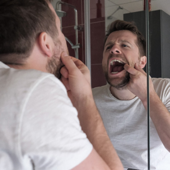 Fairfax patient checking gums in mirror