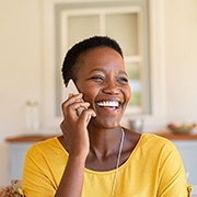 Woman in yellow shirt talking on phone at home