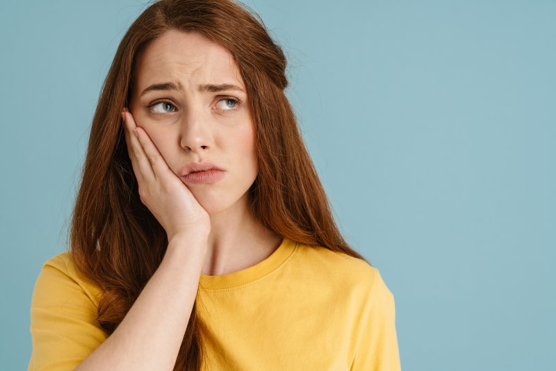 Patient holding their cheek due to dental implant sensitivity